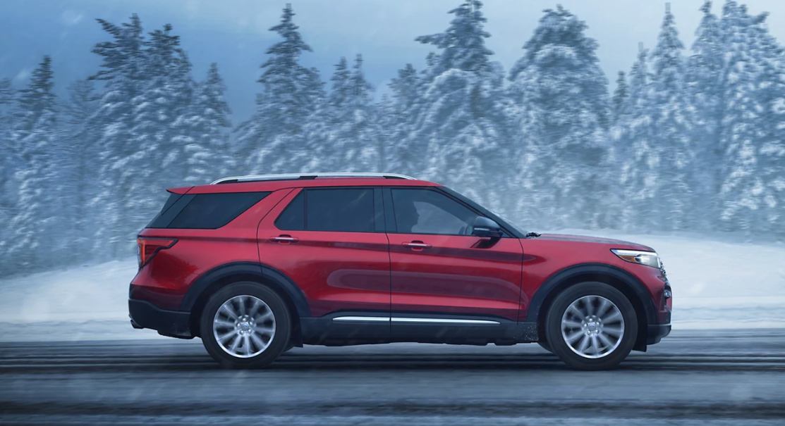 A Red Ford Explorer driving in a snowstorm.