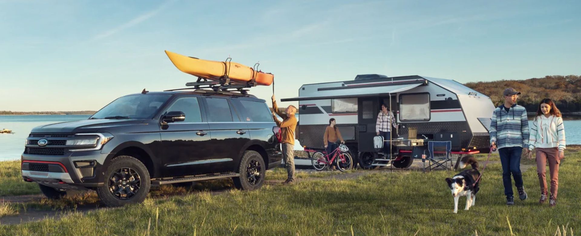 A family and their dog surround their Ford Expedition with their camper, ready for some fun!