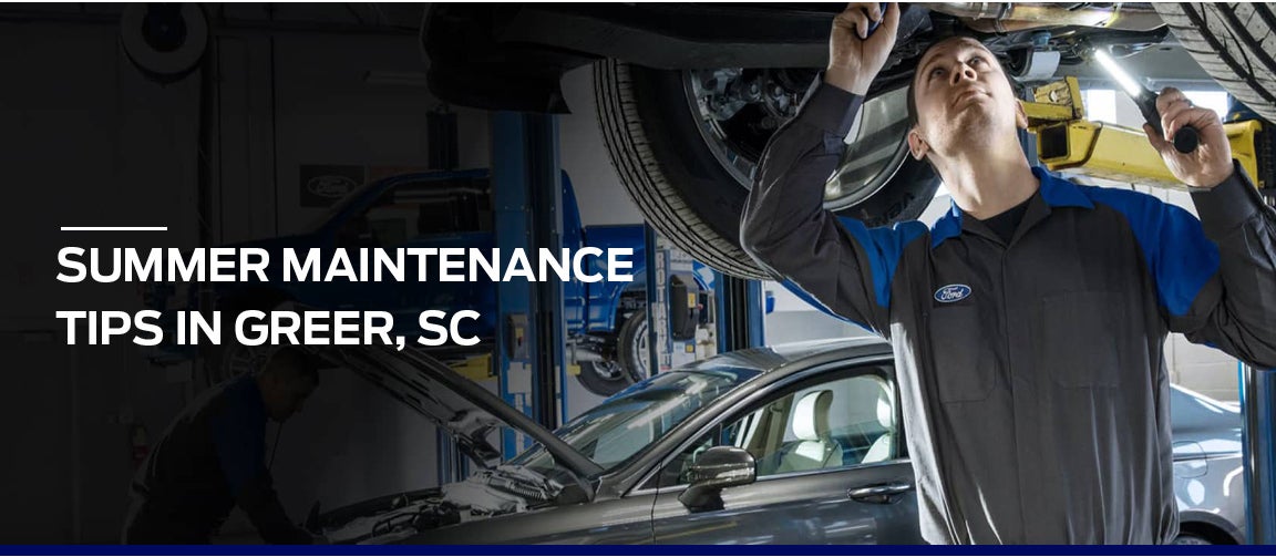 Ford Service technician inspecting a vehicle during summer maintenance.